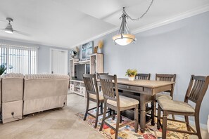 A dining area with a wooden table and chairs, a ceiling fan, and a decorative light fixture. - Snowbird Ready | Gated Pool Villa | Bonita (Bonita Springs)