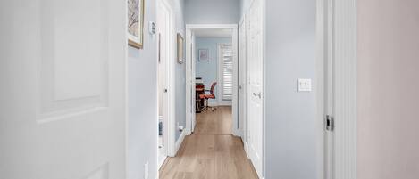 Ein Flur mit weißen Türen, Holzdielen und einer Decke mit Einbautenleuchten.