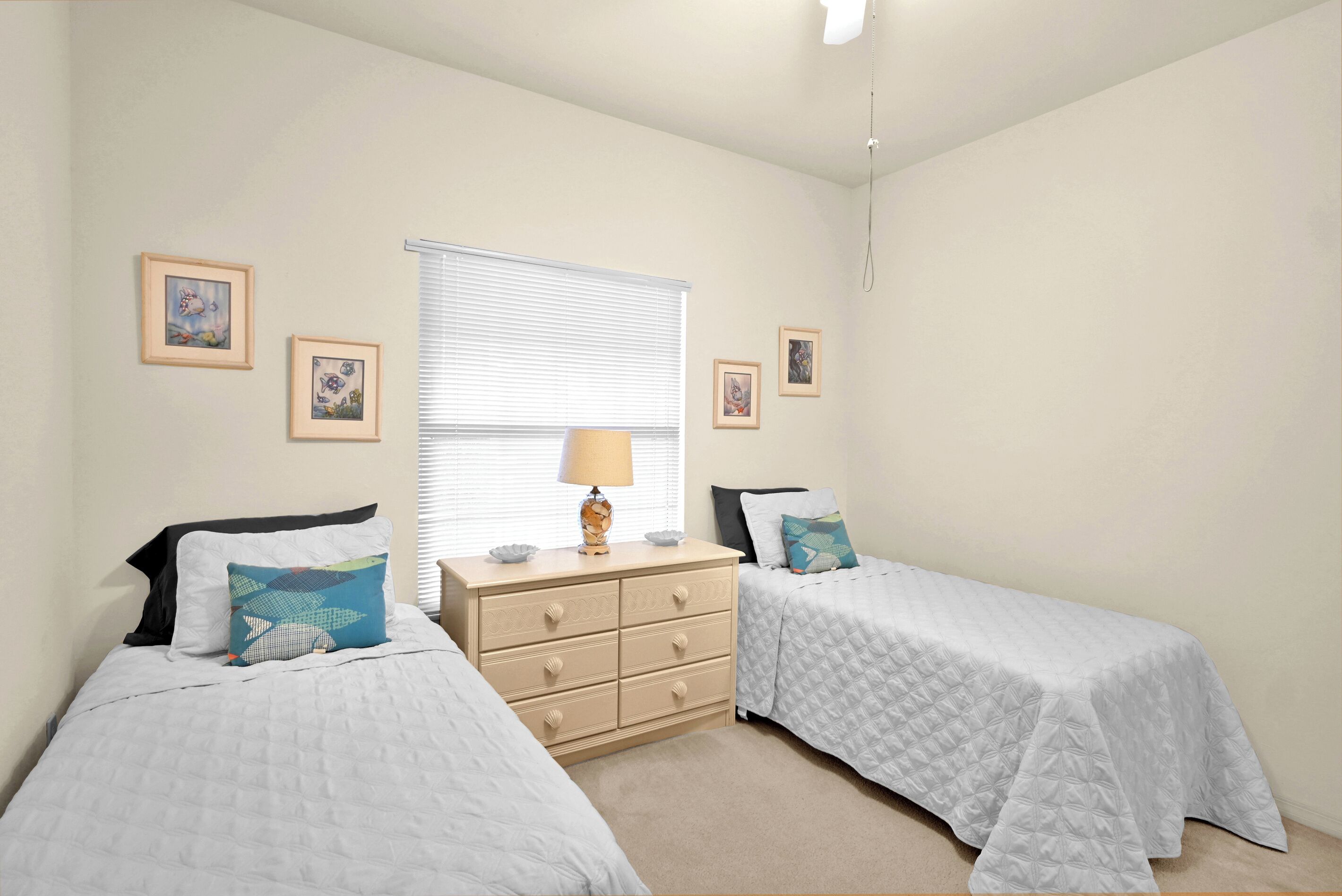 Un dormitorio con dos camas individuales, un tocador y una ventana con persianas.