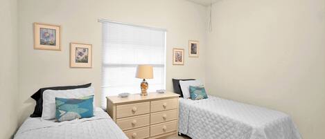 Un dormitorio con dos camas individuales, un tocador y una ventana con persianas.