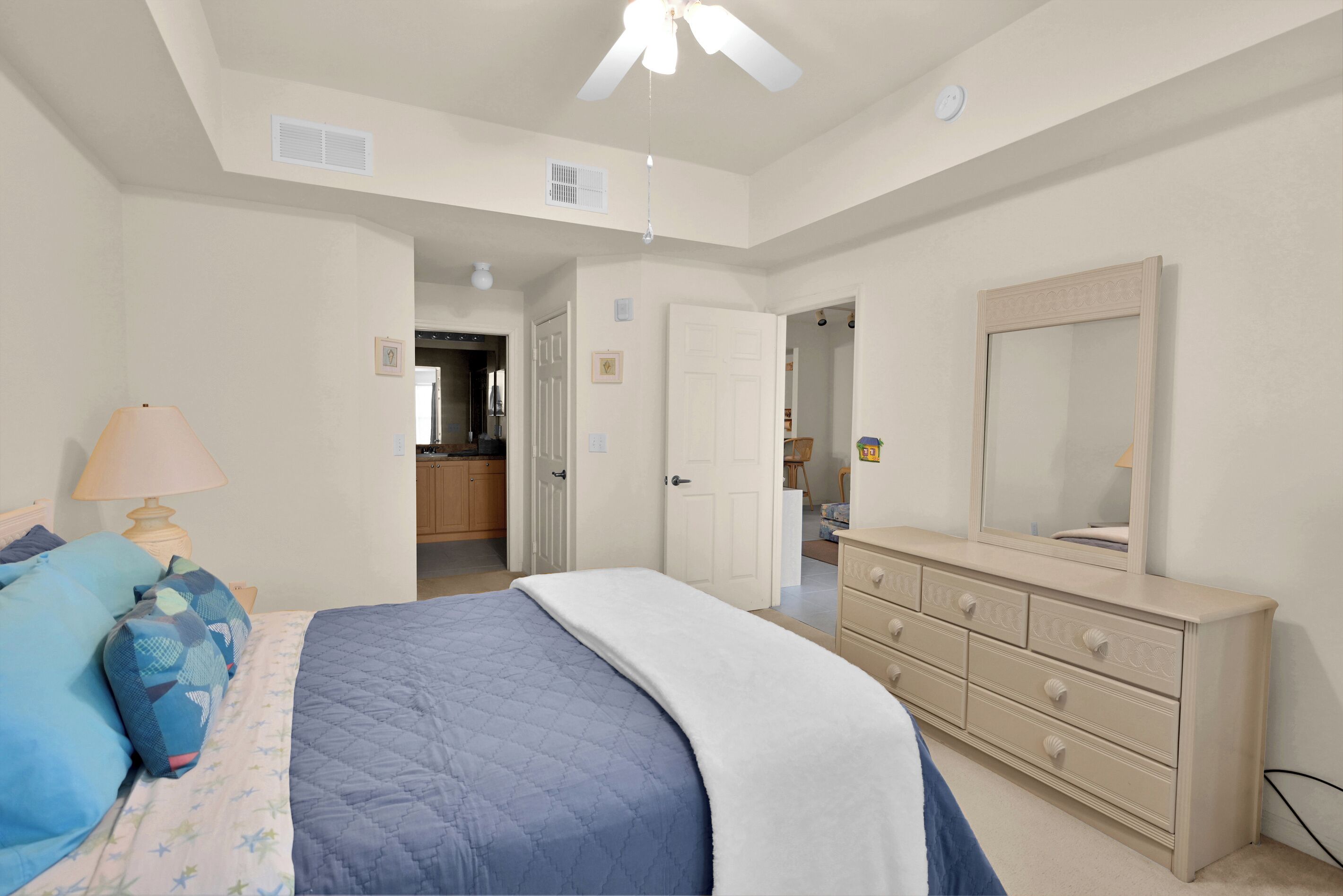 A bedroom with a bed, dresser, and a ceiling fan.