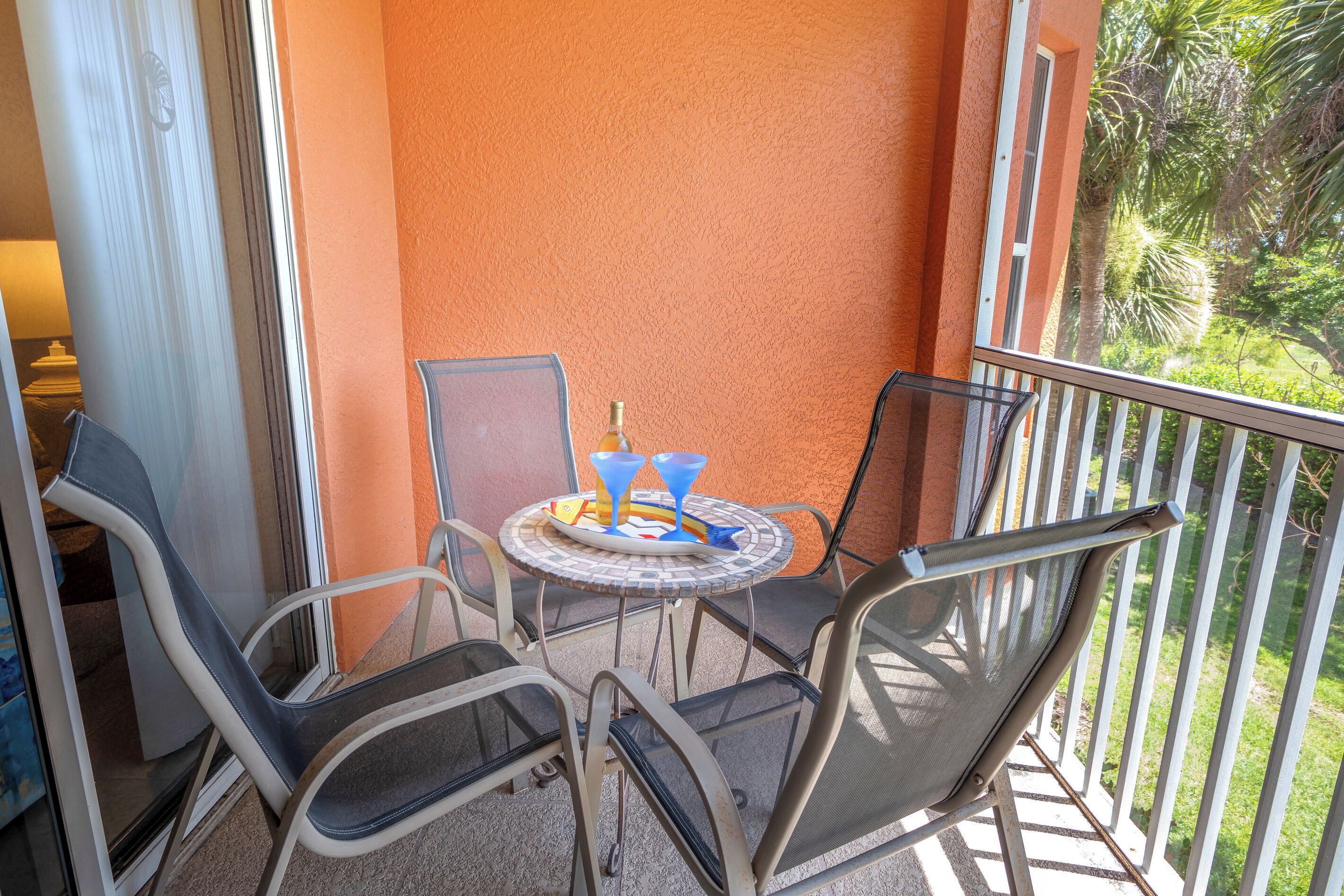 Uma varanda com mesa, cadeiras e vista para o verde.