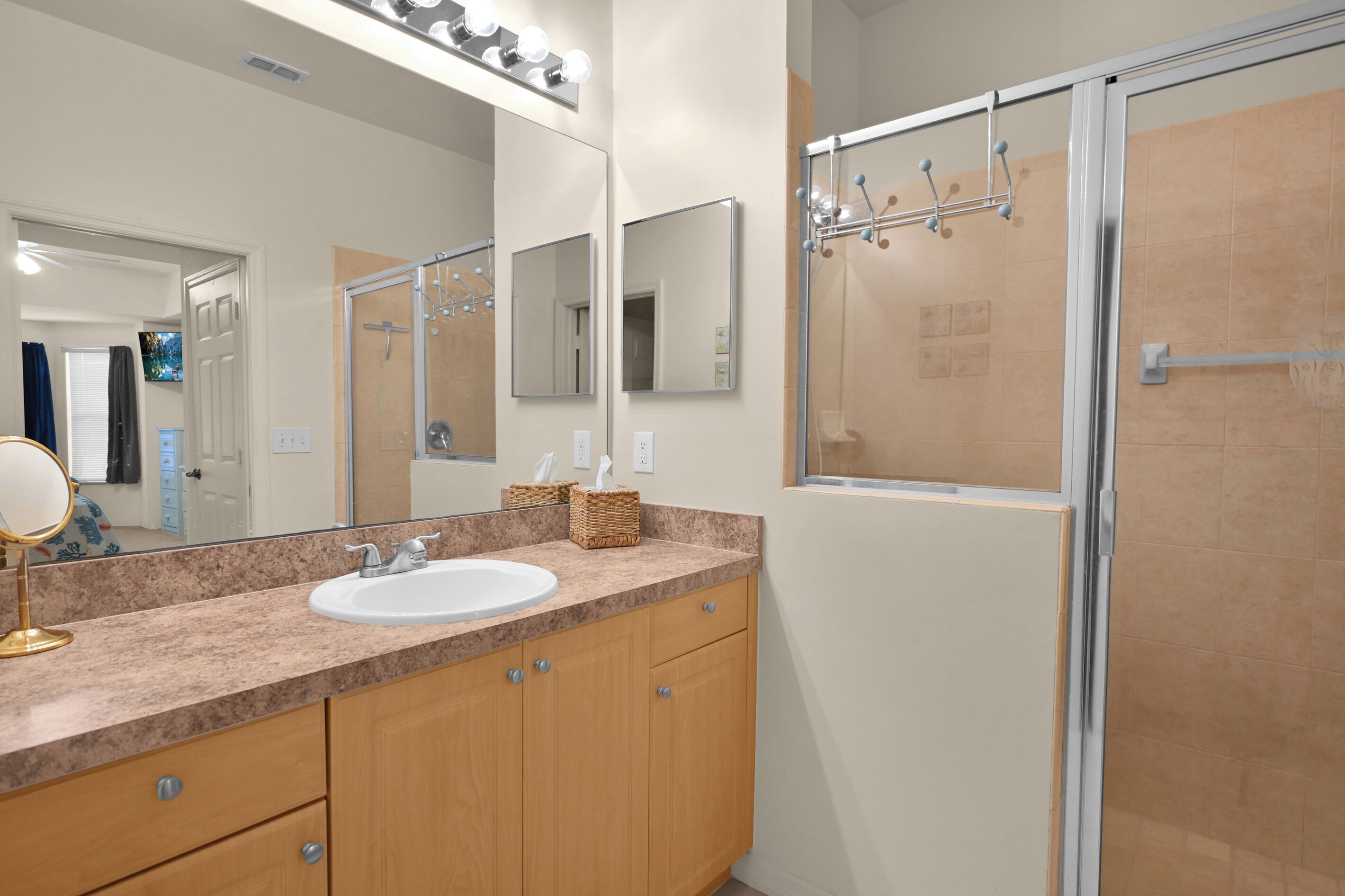 A bathroom with a sink, mirror, and shower.