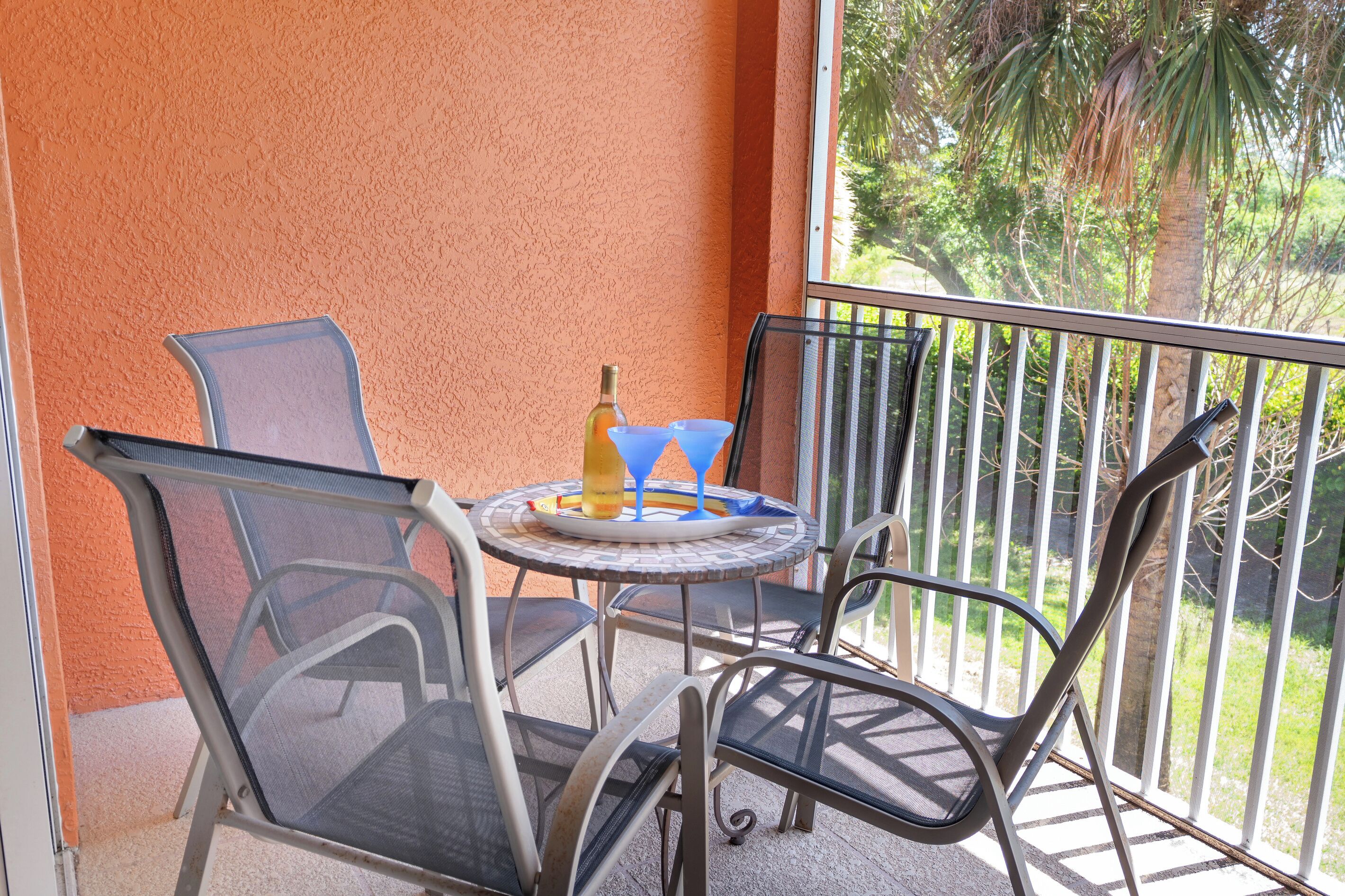 Ein Balkon mit Tisch, Stühlen und einer Flasche.