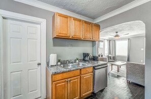 Una cocina con armarios de madera, lavavajillas, pileta y cafetera.