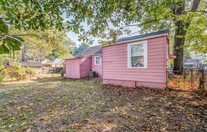 A pink single-story house with a small front yard, surrounded by trees and other houses. - Near U of Memphis & Airport - Bethel Grove Getaway (Memphis)