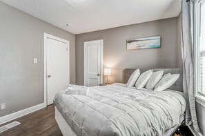 A bedroom with a bed, a nightstand, a lamp, and a painting on the wall.
