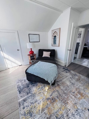 Une chambre à coucher avec un lit, une table de chevet, une lampe et une porte.