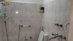 Ein Badezimmer mit Toilette, Bidet, Dusche und Deckenventilator.