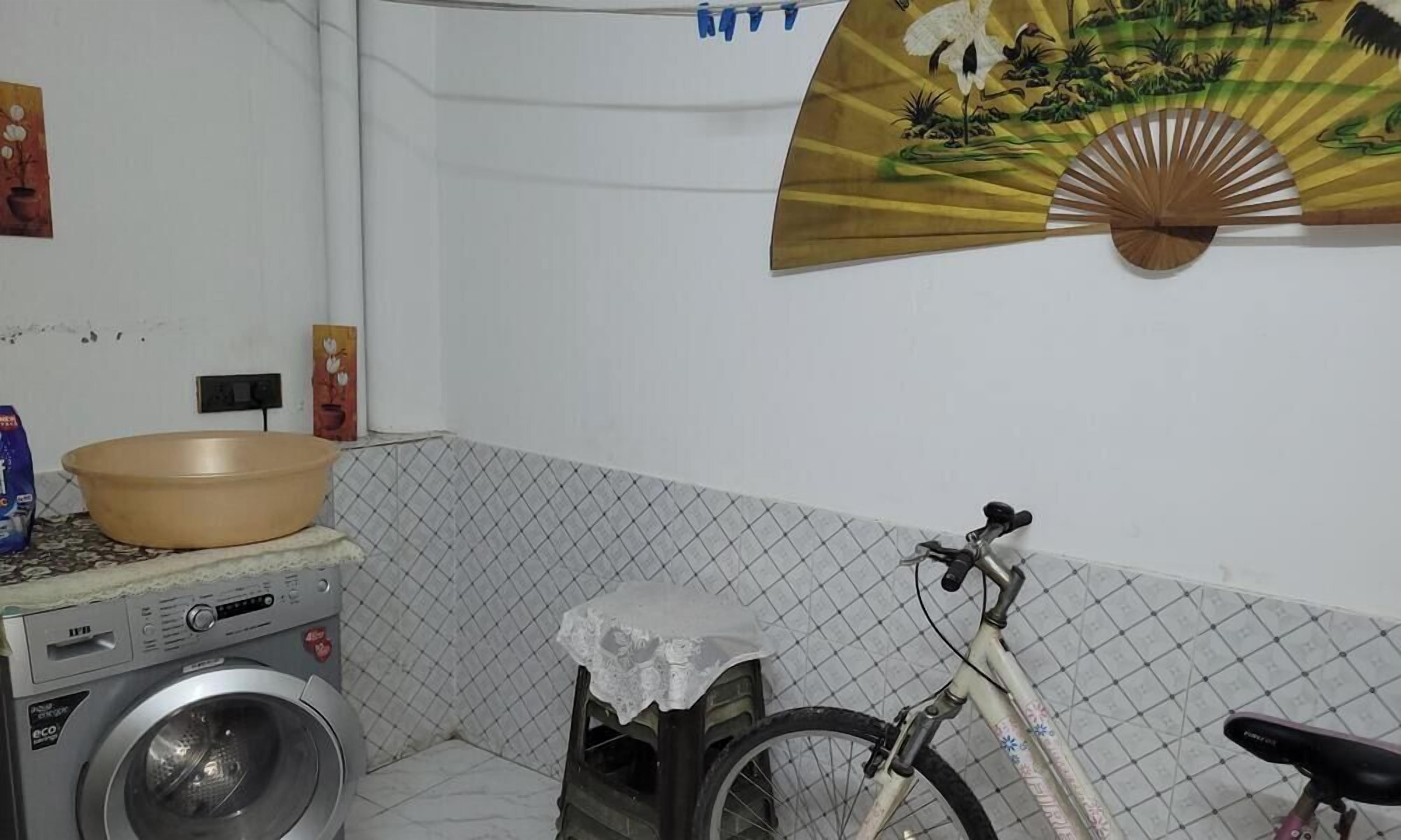 Un área de lavandería con lavadora, tendedero y bicicleta.