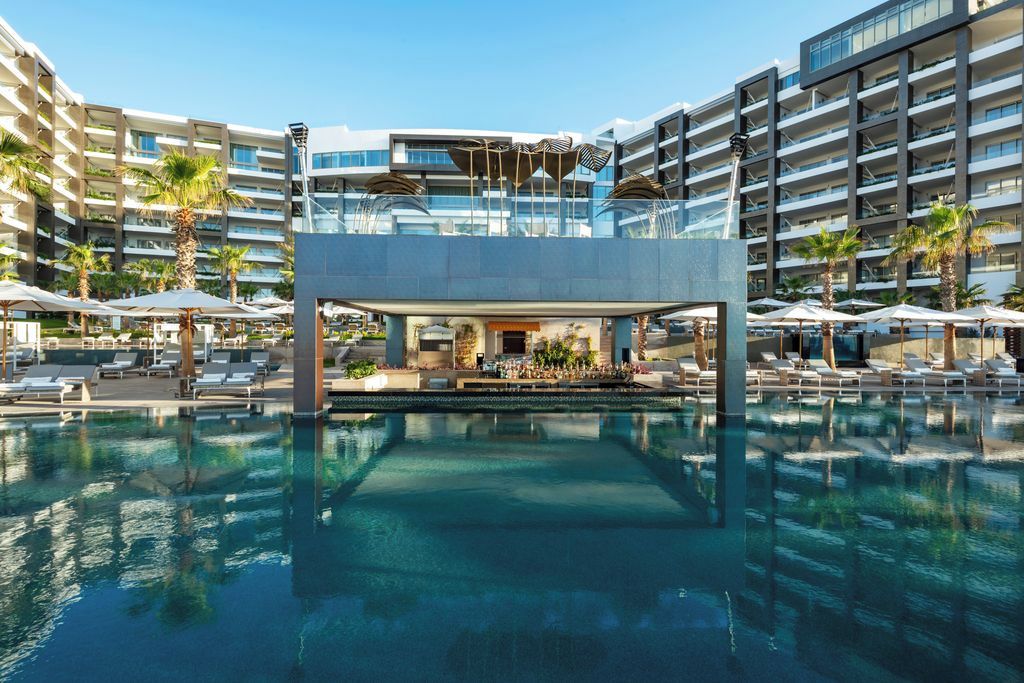 A hotel with a central pool area, multiple balconies, and outdoor seating with umbrellas.