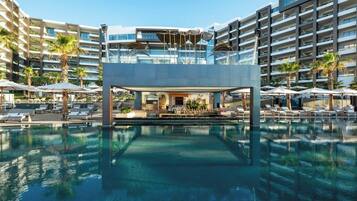 A hotel with a central pool area, multiple balconies, and outdoor seating with umbrellas.