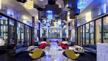A modern lobby with a central seating area, large windows, and geometric ceiling design.