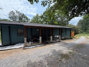 A two-story building with a covered porch and a gravel driveway.
