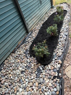 A garden bed with plants and a variety of pebbles.