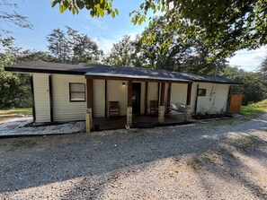 A single-story building with a porch, a small entryway, and a gravel driveway.