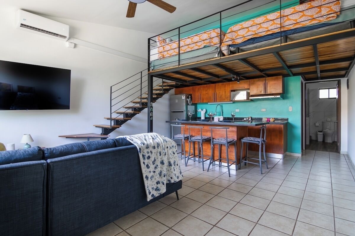 Un appartement moderne comprenant un espace de vie, une cuisine et une mezzanine avec balcon.