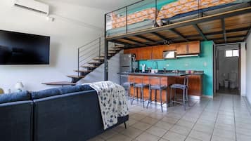 Un apartamento moderno con sala de estar, cocina y un altillo con balcón.