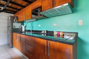 Eine Küche mit Holzschränken, einem Edelstahlkühlschrank, einem eingebauten Backofen und einer grünen Wand.