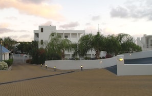 A modern building with a flat roof, surrounded by palm trees and a paved walkway. - Cozy condo sleeps 4 in upscale Oyster Pond region,AC throughout. 2nd Club Access (Oyster Pond)