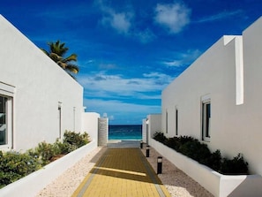 A pathway leading to a beach with white buildings on either side. - Cozy condo sleeps 4 in upscale Oyster Pond region,AC throughout. 2nd Club Access (Oyster Pond)