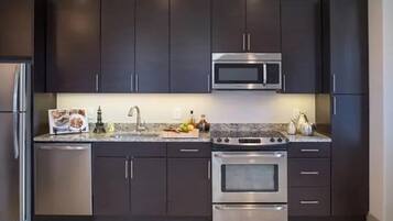 A modern kitchen with dark cabinets, stainless steel appliances, and a granite countertop.