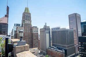 A cityscape with various buildings, including a prominent Art Deco skyscraper, modern high-rises, and a street lamp. - Harbor free indoor parking (Baltimore)
