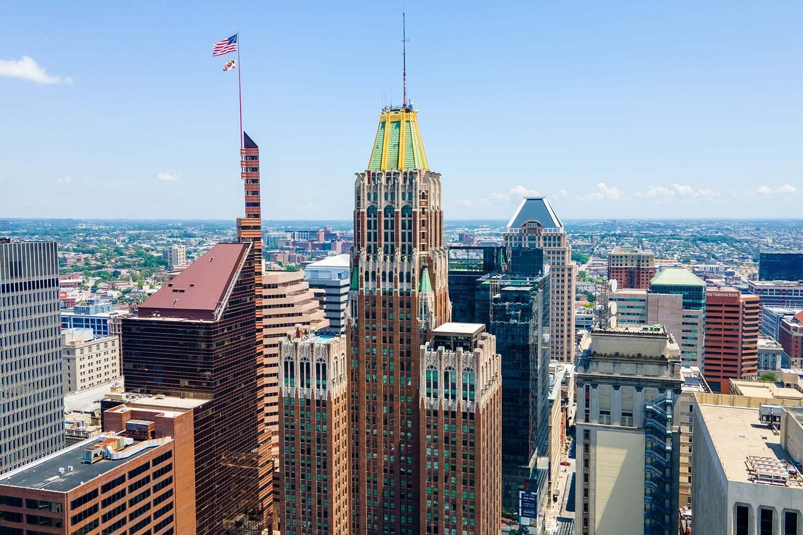A cityscape with high-rise buildings, including a prominent Art Deco skyscraper with a spire and a flag.