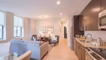A modern kitchen with dark cabinets, stainless steel appliances, and a dining area with a sofa and table.