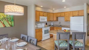 Una cocina moderna con armarios de madera, estufa blanca, microondas y refrigerador.