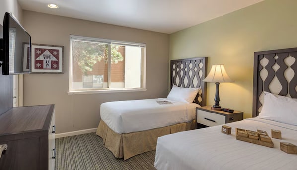 A hotel room with two beds, a TV, a window, and a wall-mounted sign.