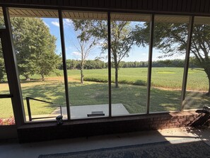 A room with large windows overlooking a grassy field and trees.