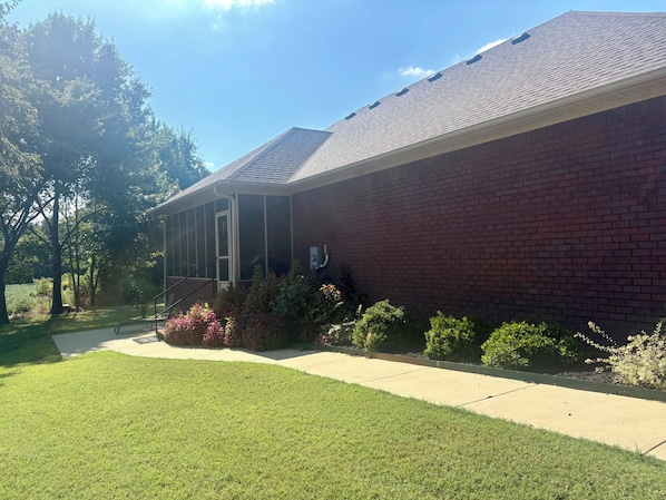 A building with a brick exterior, a covered porch, and a well-maintained lawn.
