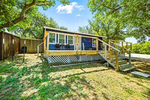 A small wooden cabin with a deck and a staircase leading to a covered area. - Lakefront Blue Dream Home with Deck (Little Elm)