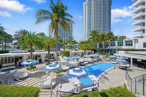 A resort with a swimming pool, sun loungers, and palm trees. - Stunning Ocean View Studio at Tresor Fontainebleau Miami Beach (Miami Beach)