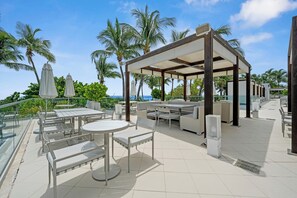 An outdoor patio with tables and chairs, a covered seating area, and a view of the ocean. - Stunning Ocean View Studio at Tresor Fontainebleau Miami Beach (Miami Beach)