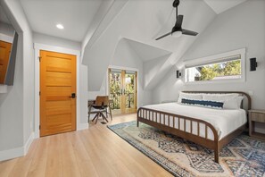 A bedroom with a sloped ceiling, a bed, a chair, a window, and a door. - Seasonal Retreat | Private Yard w/Sauna & Spa (Whitefish)