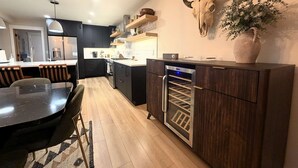 Eine moderne Küche mit dunklen Schränken, einem eingebauten Backofen und einem Weinkühlschrank.