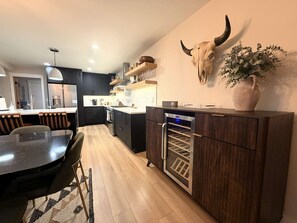 Eine moderne Küche mit dunklen Schränken, einem eingebauten Backofen und einem Weinkühlschrank.