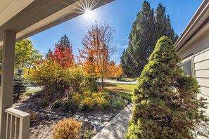 A garden with a variety of trees and shrubs, a stone pathway, and a house in the background. - Seasonal Retreat | Private Yard w/Sauna & Spa (Whitefish)