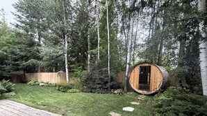 Eine Holzhütte mit einer Tür, umgeben von einem gepflegten Rasen und Bäumen.