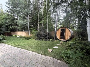 Eine Holzhütte mit einer Tür, umgeben von einem gepflegten Rasen und Bäumen.
