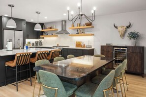 A modern kitchen with a central island, bar stools, and a dining table. - Seasonal Retreat | Private Yard w/Sauna & Spa (Whitefish)