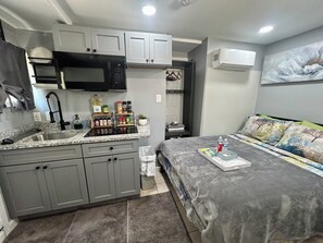 A compact kitchenette with a microwave, sink, and storage cabinets.