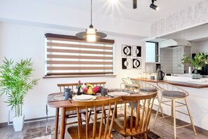 Une cuisine moderne avec un coin repas, comprenant une table ronde en bois, des chaises et un luminaire suspendu.