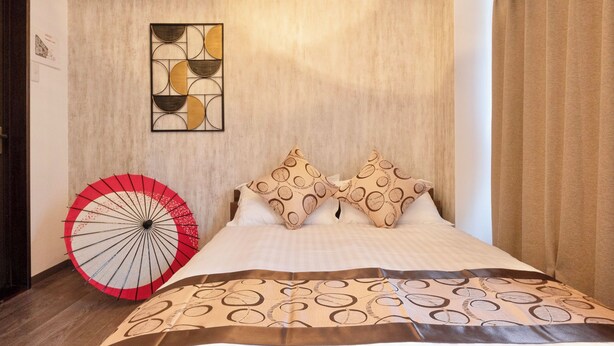 Una camera d'albergo con un letto, un elemento decorativo a parete e un ombrello rosso.