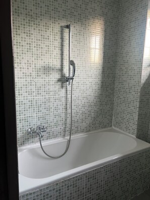 Een badkamer met een douche en een badkuip, beide met betegelde wanden.