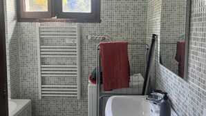 A bathroom with a white sink, a mirror, a window, and a towel rack.