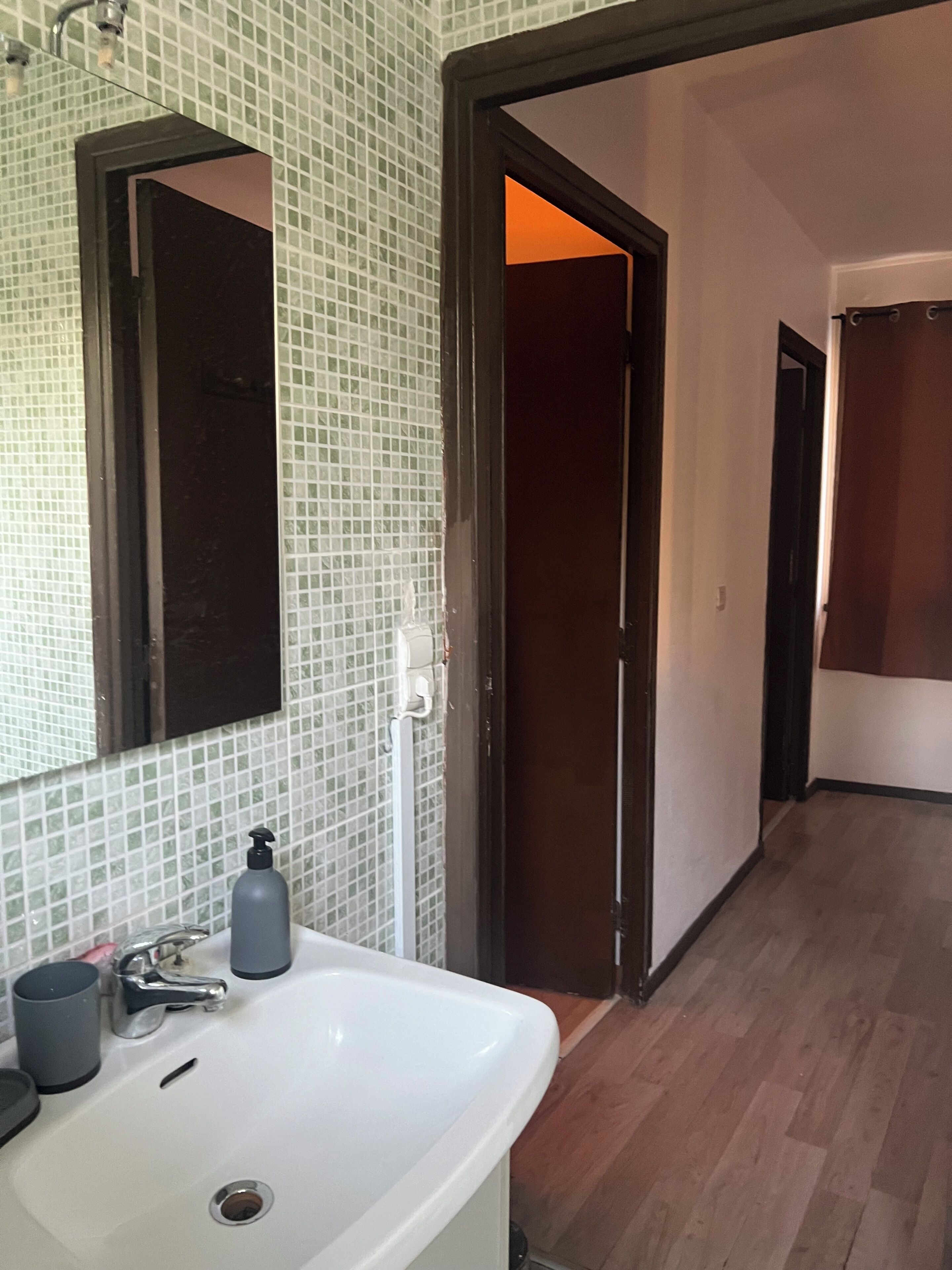 Een badkamer met een wit wastafel, een spiegel en een douche.