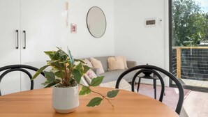 Een modern interieur met een houten eettafel, een potplant, een bank en een grote spiegel aan de muur.